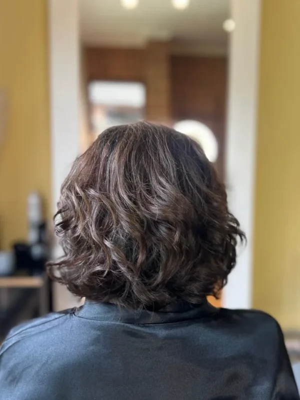 Mujer juven de espalda con un corte de cabello rizado moderno con movimiento y estilo en la peluquería en Concón - Reñaca, realizado por Carola Vogue Estilista Experta en rizos.